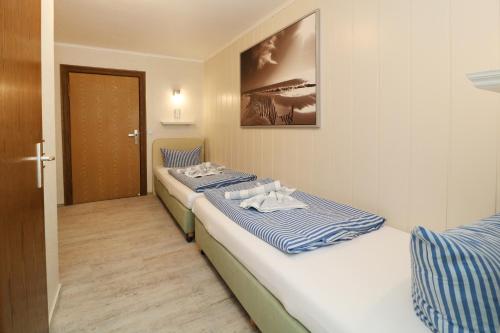 two beds in a small room with a door at Koserow Hotel Wald und Meer in Koserow