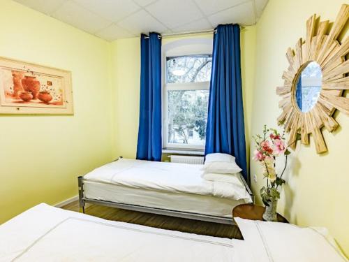 a bedroom with two beds and a window with blue curtains at Attic apartment in villa! in Berlin