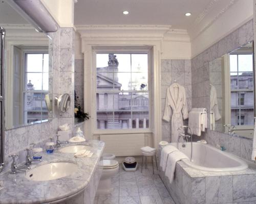 uma casa de banho com 2 lavatórios, uma banheira e um WC. em The Merrion Hotel em Dublin