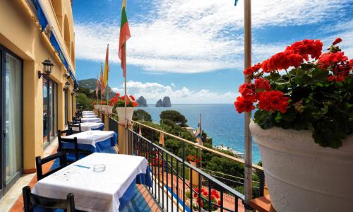a row of tables on a balcony with a view of the ocean at Hotel Weber Ambassador in Capri