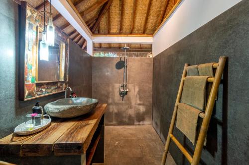 a bathroom with a stone sink and a wooden table at Breathe Villa Meno in Gili Meno