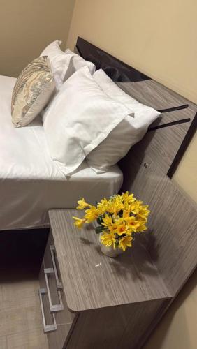 a bed with pillows and a table with flowers on it at Mwenda Residence in Ongwediva