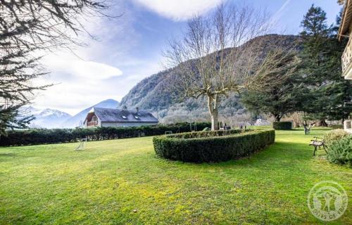 a park with a house and a tree in a field at Aubépine in Cadéac