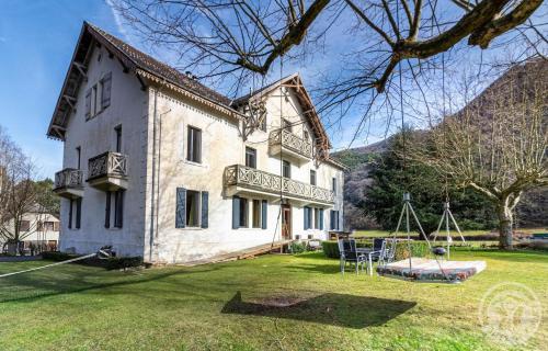 a large white house with a playground in the yard at Aubépine in Cadéac
