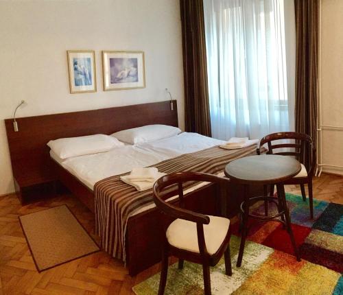 a bedroom with a bed with a table and chairs at Hotel & Penzión Grand Matej in Banská Štiavnica