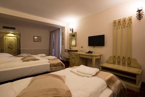 a hotel room with three beds and a television at Hotel Aviator Boutique in Otopeni