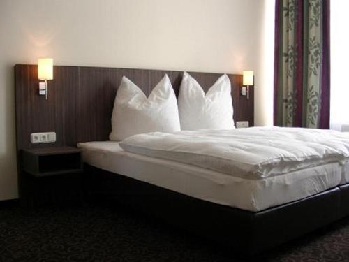 Schlafzimmer mit einem Bett mit weißer Bettwäsche und Kissen in der Unterkunft Pension Luft in Dresden