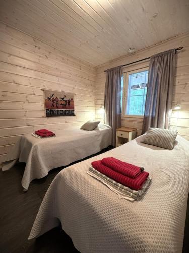 a bedroom with two beds with red pillows on them at Lumilyhty B in Äkäslompolo