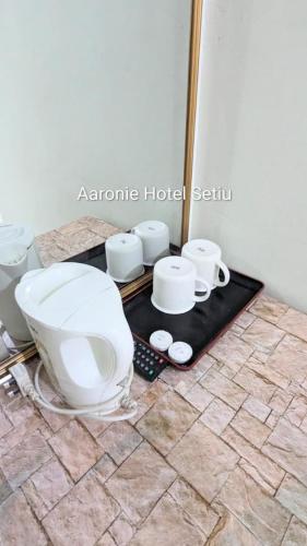 a bathroom with a toilet and cups on a table at Aaronie Hotel Setiu in Kampong Burok