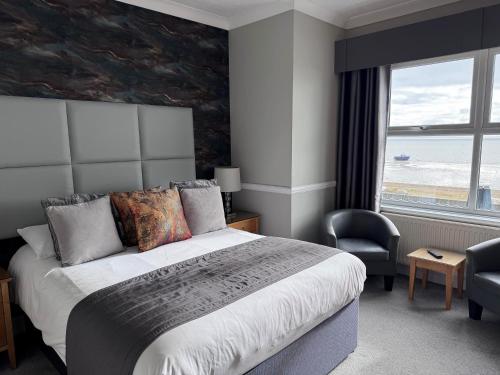 a bedroom with a large bed and a large window at Camelia Hotel in Southend-on-Sea