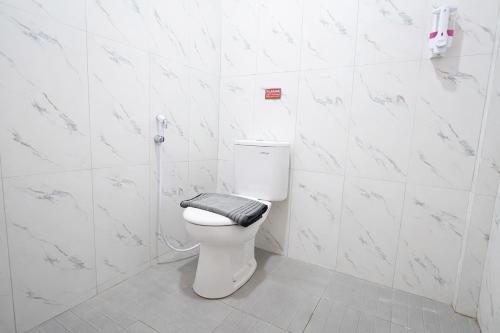 a bathroom with a white toilet with a black seat at Tripletree Kenaro Hotel in Blimbing