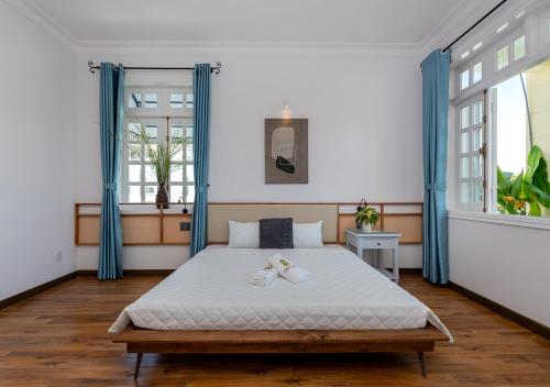 a bedroom with a large bed with blue curtains at AnNam Village 4 in Vung Tau