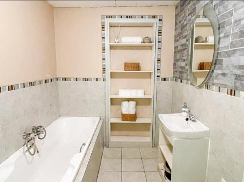 a white bathroom with a tub and a sink at Studio APT with pool and jacuzzi at the golf course in Johannesburg