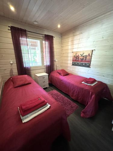 two beds in a room with red sheets at Lumilyhty A in Äkäslompolo
