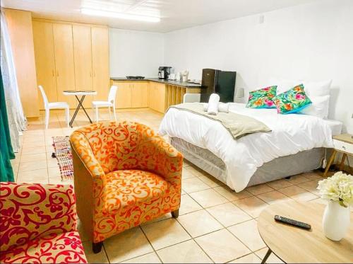 a bedroom with a bed and a chair and a table at Studio APT with pool and jacuzzi at the golf course in Johannesburg