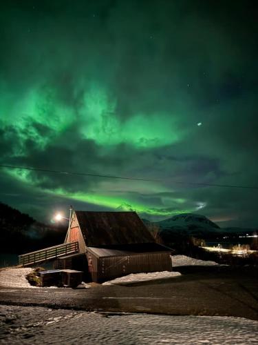a barn under a cloudy sky with a green sky at Big cabin in Lyngen Fjords in Jægervatnet