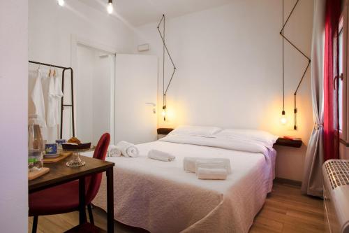 a bedroom with a white bed and a table with a chair at B&B da Baba in Ghizzano