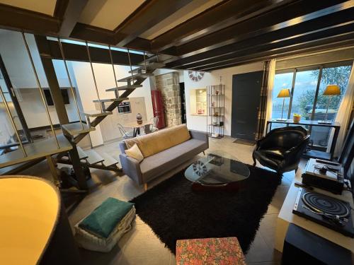 a living room with a couch and a stair case at Les lauriers du loft in Pazayac