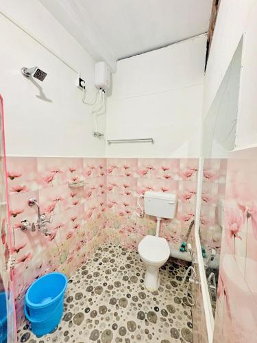 a bathroom with a toilet and pink flowers on the wall at Mannat Lodge in Hailākāndi
