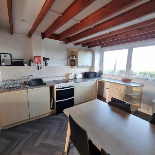 a kitchen with a table and a large window at Penrhyn Cottage Tyn Don in Llanengan