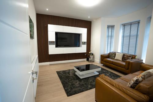a living room with a couch and a tv at Luxury 6 Bed near city centre with Cinema Room & games room plus 5 bathrooms in Manchester
