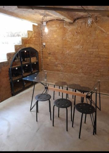 a glass table and four chairs in a room with a brick wall at Pupi Apartmanház in Balatonlelle