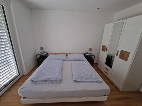 a white bedroom with two beds and a window at Ferienwohnung Jolina in Lustenau
