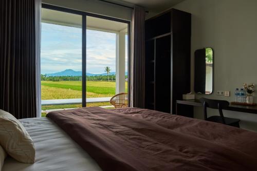ein Schlafzimmer mit Bett und Fenster mit Aussicht in der Unterkunft Leafy's Lodge in Padangnegeri