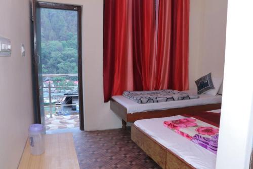 a room with two beds and a window with red curtains at Hotel Vivek Palace in Uttarkāshi