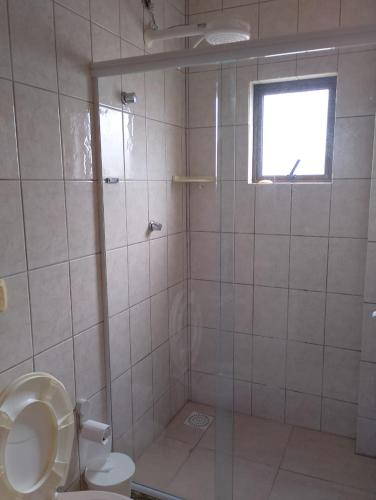 a bathroom with a shower with a toilet and a window at Praias do Sul in Cabo Frio