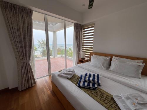 a bedroom with a bed with a view of the ocean at Royal Wave, Beachfront, Nilaveli in Trincomalee