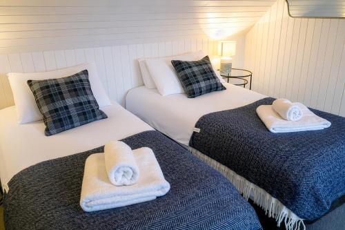 two beds with towels on them in a room at Plockton Distillery Flat in Plockton