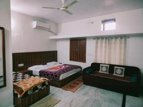 a bedroom with two beds and a couch in it at Laxmanji villas in Mount Ābu