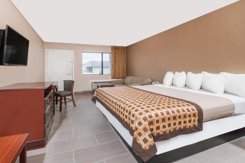 a hotel room with a large bed and a desk at Deluxe Inn Denton in Denton