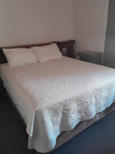 a bed with white sheets and pillows in a bedroom at Dudes guesthouse in Francistown