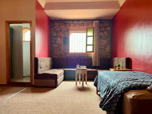 a bedroom with red walls and a bed and a window at Villa Sun and Chill, Ferme d'hôtes familiale avec piscine animée, restaurant et jardin près de Safi in Safi