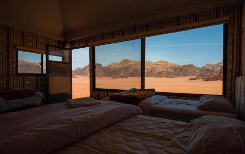 a room with three beds and a view of the desert at Milky Way Bedouin Camp in Wadi Rum