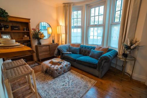 a living room with a blue couch and a table at Period apartment in the heart of Bournemouth in Bournemouth