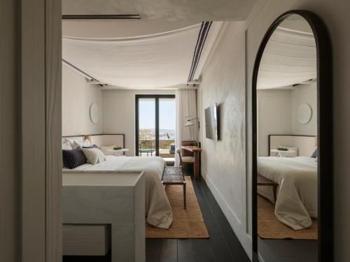 una camera da letto con due letti, un tavolo e uno specchio di Anandes Hotel a Mykonos Città
