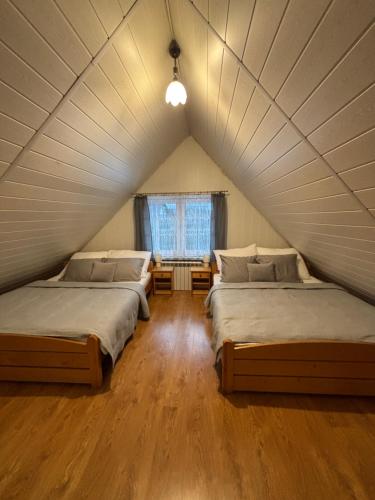 two beds in a room with a attic at Domek u Hani - domek 6 osobowy, z ogrodem i tarasem, Wisła in Wisła