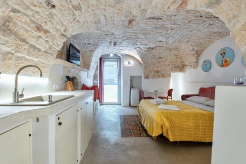 a kitchen with a bed in a room with a stone wall at Le Piccole Case Bianche in Ostuni