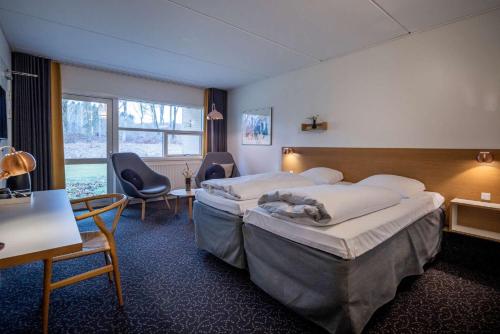 a hotel room with two beds and a table and chairs at Comwell Rebild Bakker in Skorping