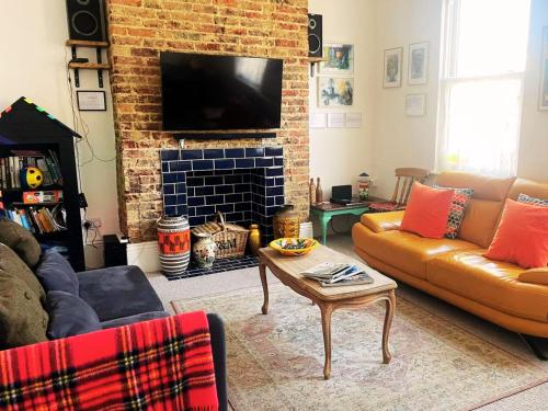 a living room with a couch and a brick fireplace at GENSING LODGE STUNNING SEASIDE MAISONETTE in St. Leonards