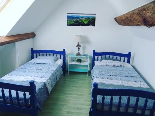 a bedroom with two beds and a table with a lamp at Gîte Le Four à Pain, 2 chambres, 2km du centre de Dole, in Dole