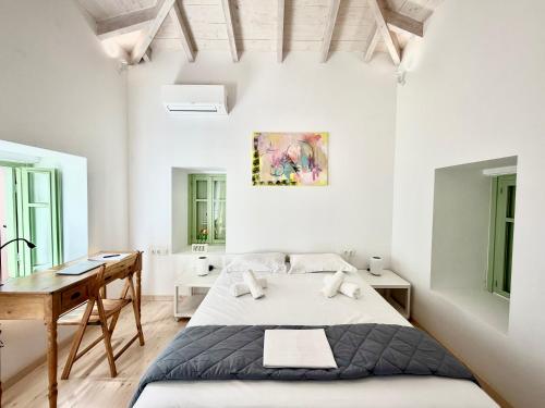 a white bedroom with a bed and a desk at Central Suites Aegina 5 in Egina