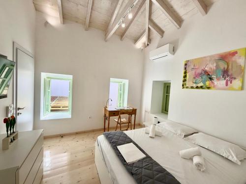 a white room with a bed and a desk at Central Suites Aegina 5 in Egina