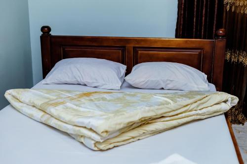 an unmade bed with two pillows and a blanket at Hulcity valley hotel in Kampala