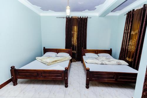 two beds in a room with blue walls at Hulcity valley hotel in Kampala