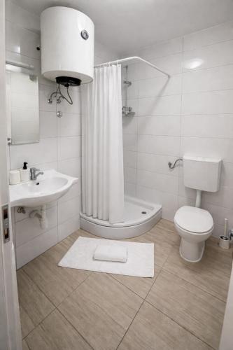 a white bathroom with a toilet and a sink at Studio apartman ANNI, Self CHECK-IN in Osijek
