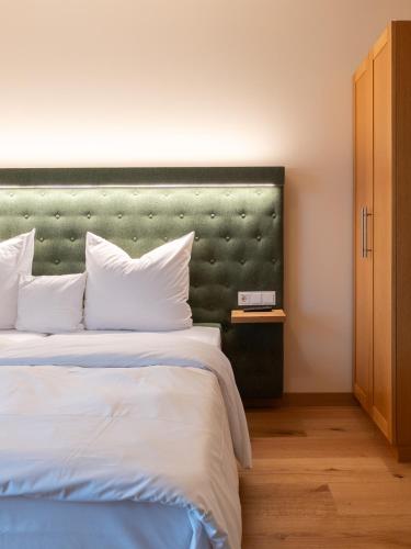 a bedroom with a large bed with a green headboard at Gutshotel Odelzhausen in Odelzhausen